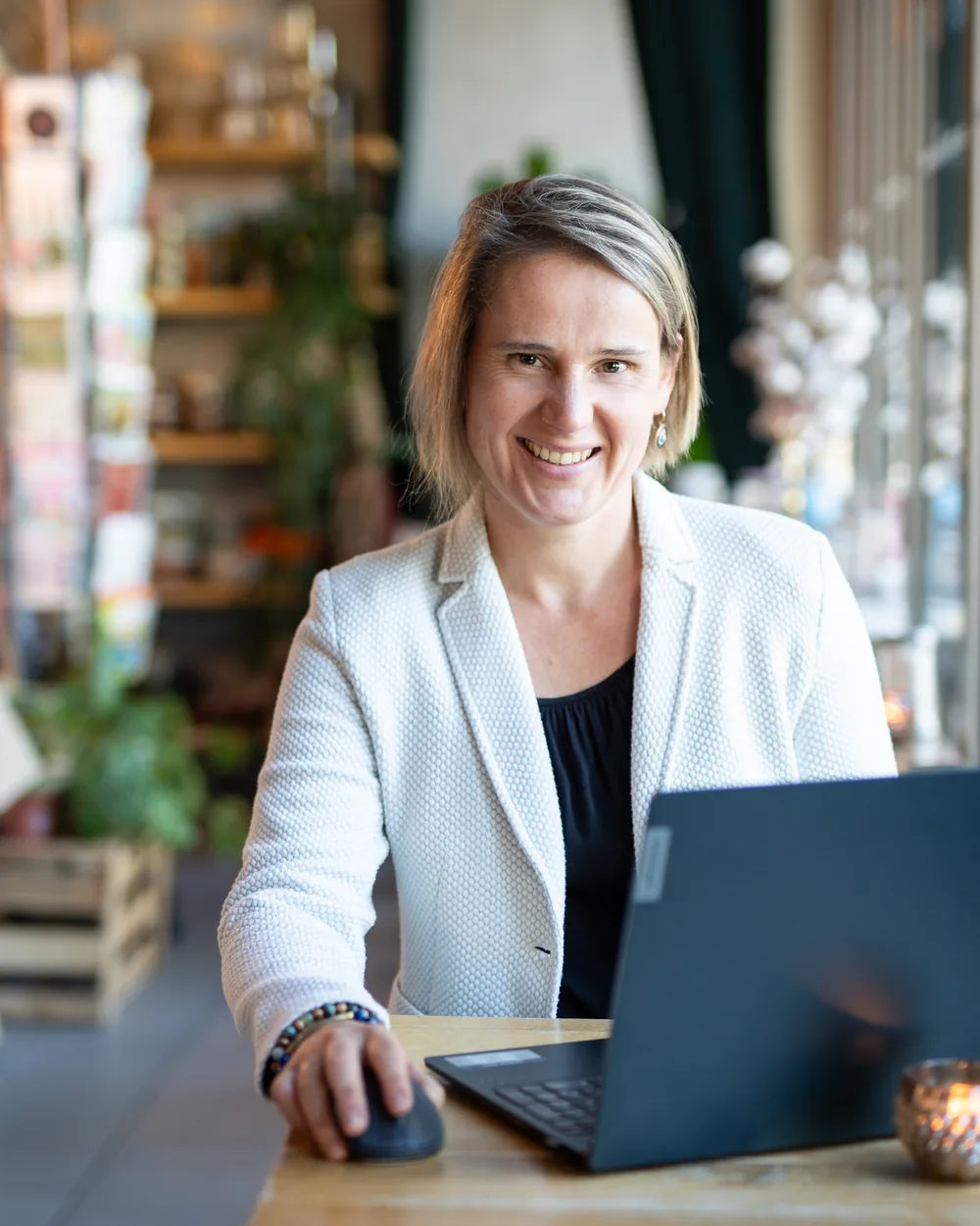 Janine Hammer lächelnd am Laptop in einem Café